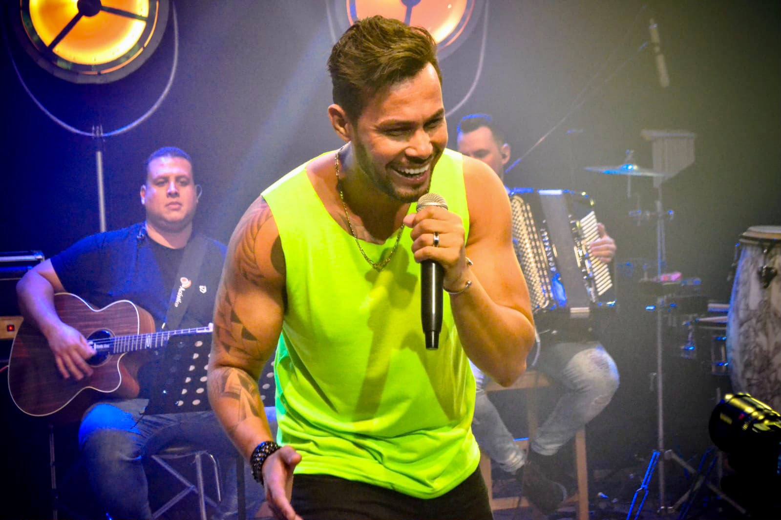 Ricky Moreira cantando no palco com a banda ao fundo