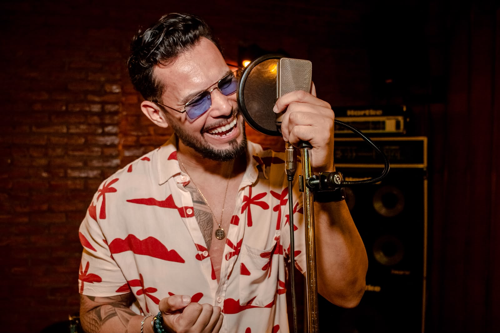 Ricky Moreira sorrindo diante do microfone de estúdio