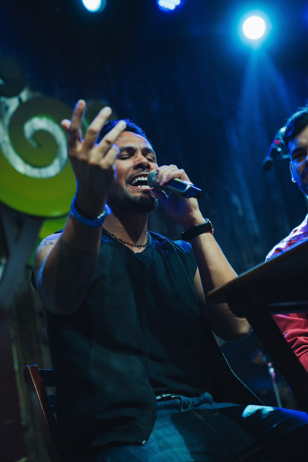 Ricky Moreira cantando no palco com iluminação azul