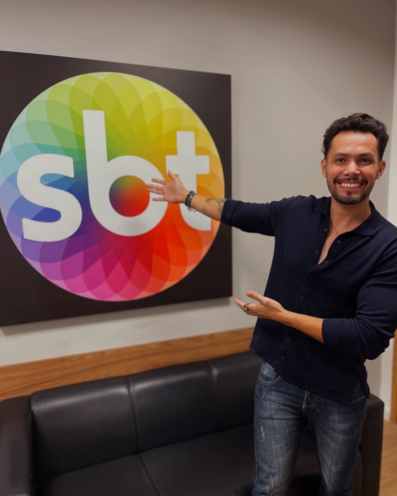 Ricky Moreira diante do logo do SBT