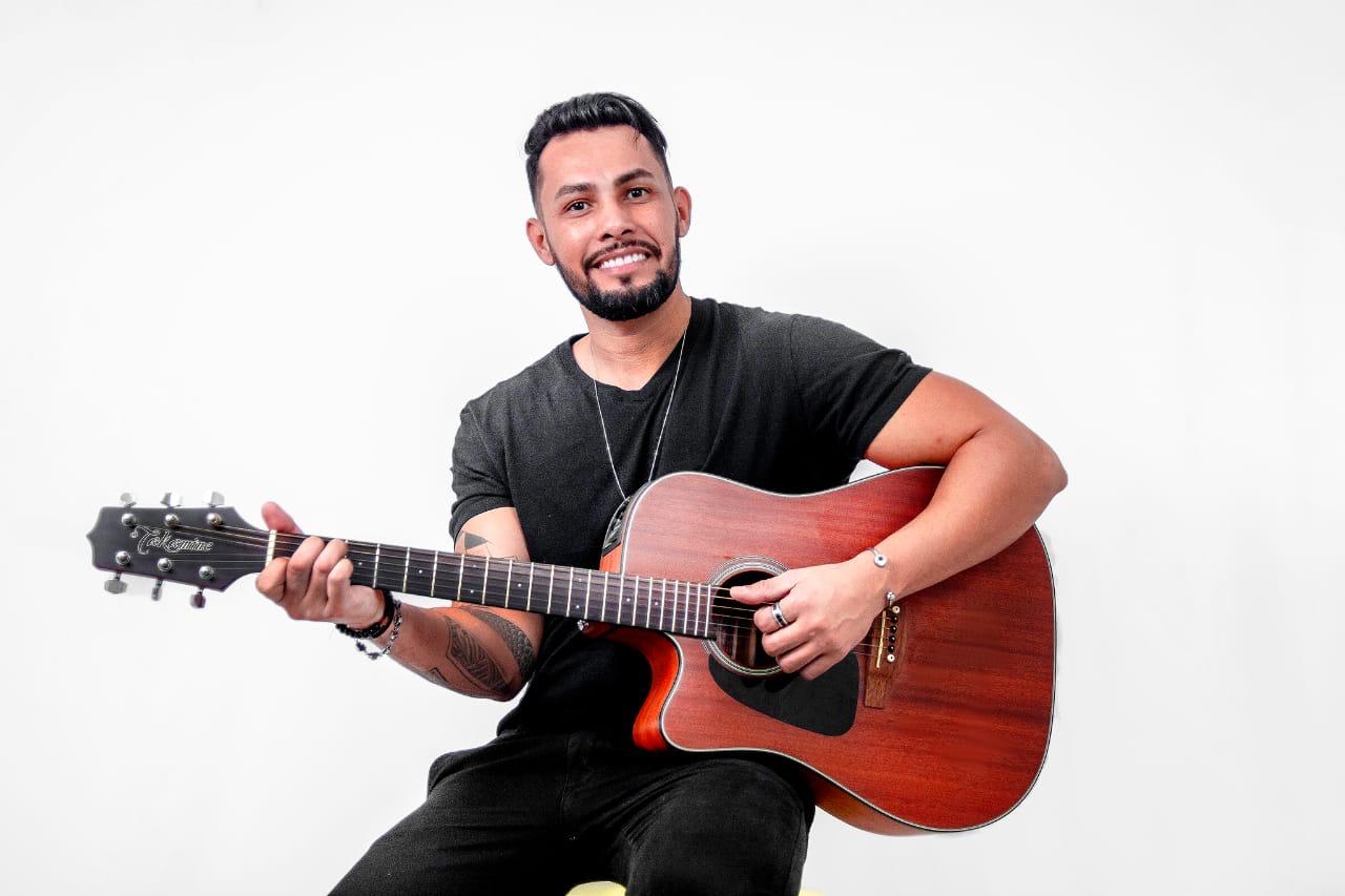 Ricky Moreira sorrindo e tocando violão