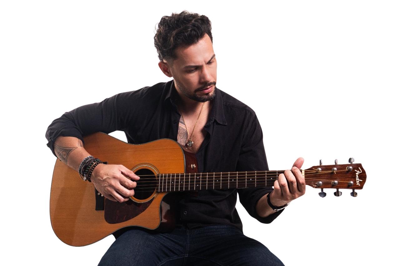 Ricky Moreira sentado tocando violão
